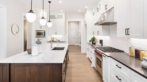 Modern kitchen remodel in Temecula featuring white shaker cabinets, a large quartz waterfall island, stainless steel appliances, custom storage solutions, and hardwood flooring designed to increase home value and deliver a high return on investment.