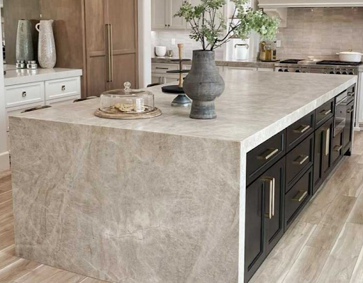 Bright modern kitchen with white cabinets, marble island, cane-back stools, and wood range hood.